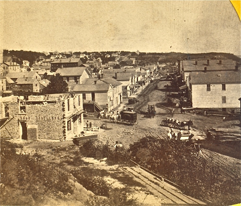 This is a later view than the previous photo, showing the construction of the brick building on the corner of Nelson and Main Streets. This photo may have been taken from the hillside or the building that stood at this location. The photo is from the John Runk Collection, courtesy of the Stillwater Public Library.