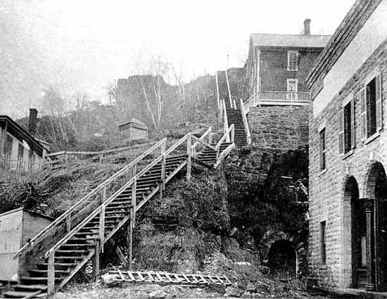 This view up the stairs does after the construction of the brick building in the foreground. The stairs are still wooden. This photo is from the John Runk Collection, courtesy of the Stillwater Public Library.