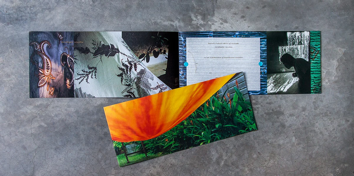 The inside spread, with translucent invitation sheet held in place by a pair of cyan round stickers and text printed in gold. A information sheet is inserted into the invitation card.