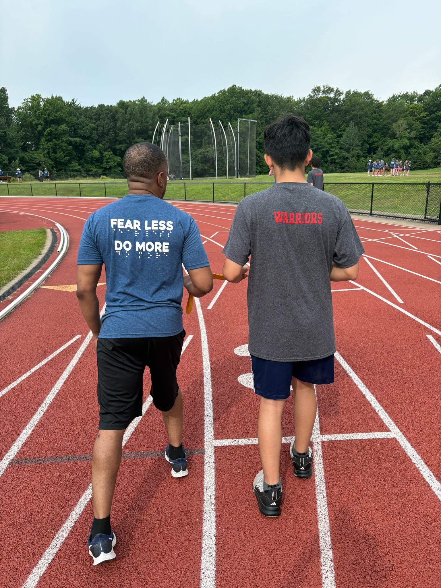 Volunteer and athlete at the track start line preparing to tandem run in a race