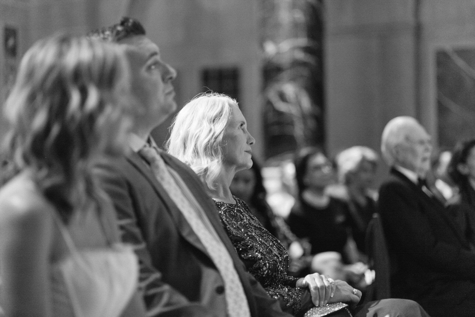 Black and white photo of women and men sitting in an audience, attentively listening to a presentation or event.