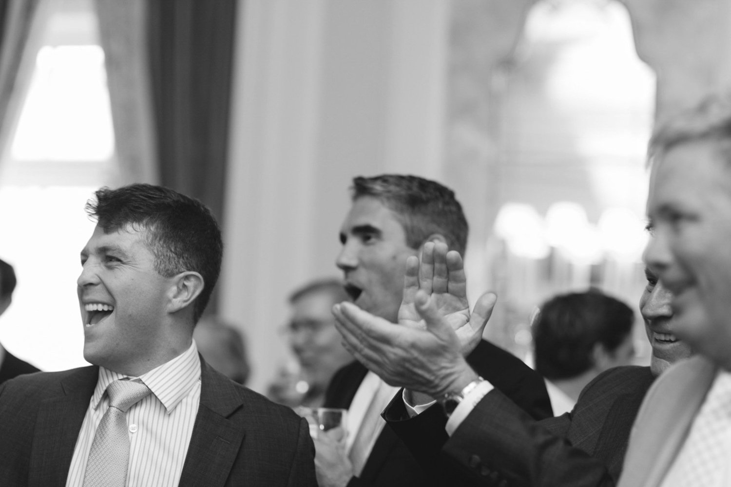 People at a formal event laughing and clapping in a banquet hall.