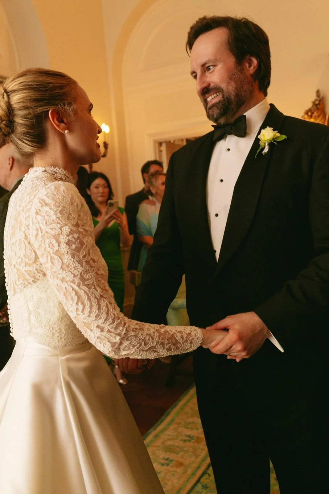A bride and groom holding hands and gazing at each other during their wedding ceremony.