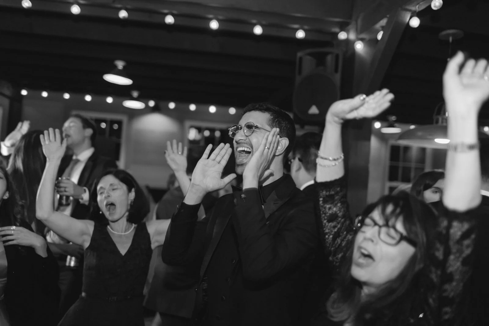 People dancing and celebrating at a party or event in a dimly lit indoor space.
