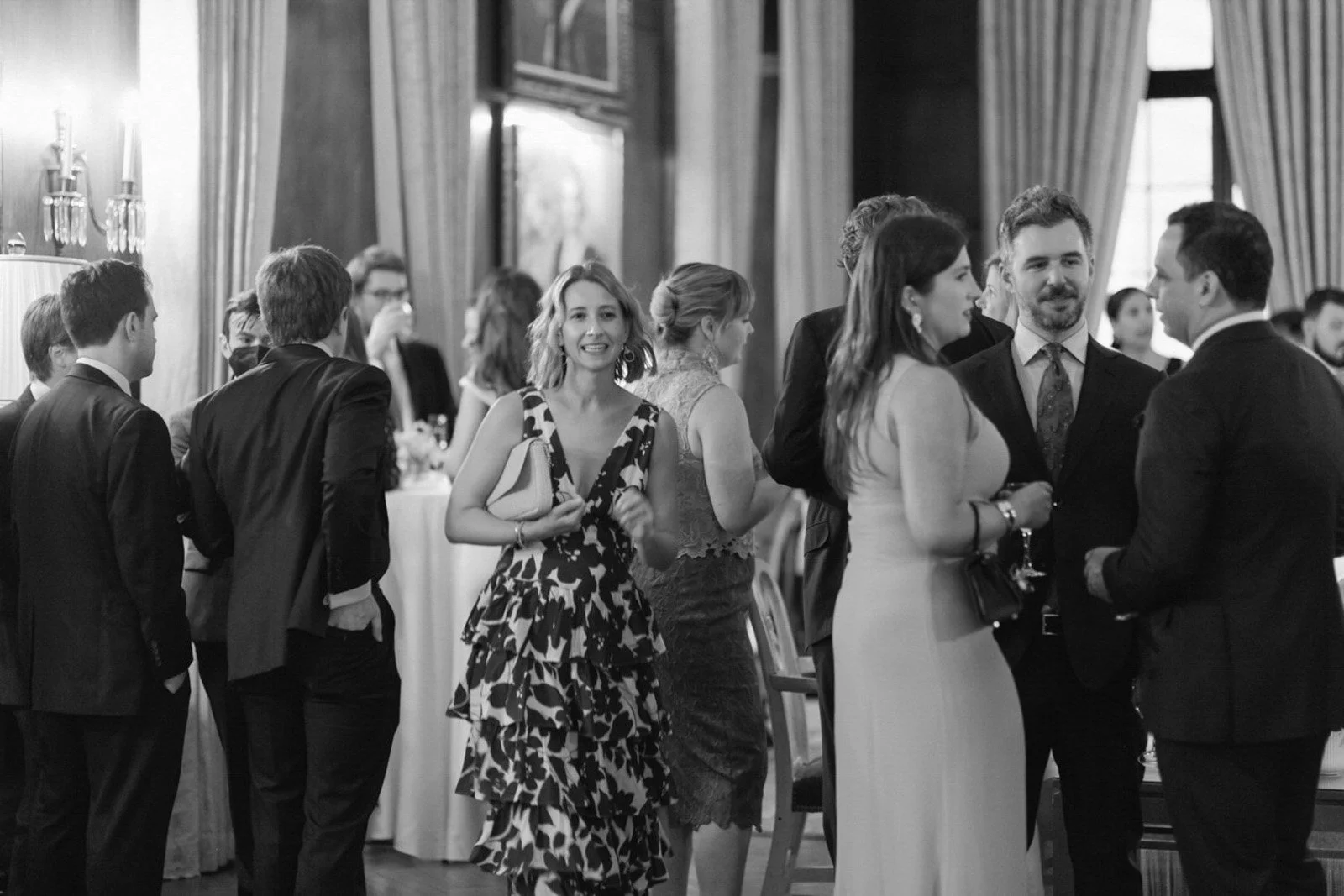 A group of well-dressed people chatting and socializing at an indoor formal event or reception.