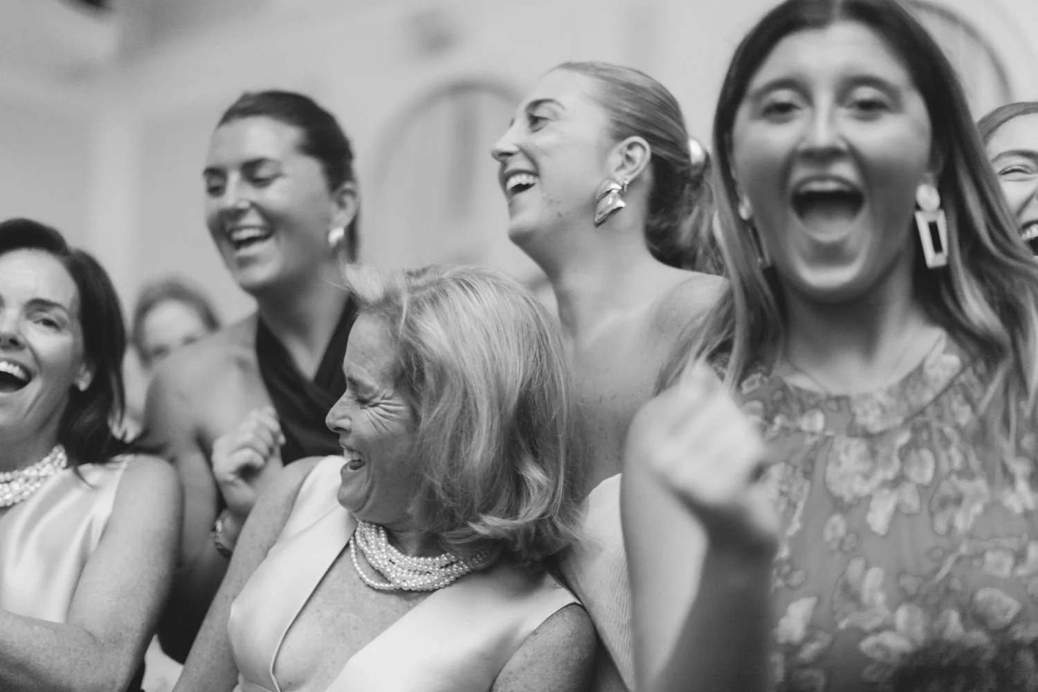 Group of women laughing and enjoying a moment together at an event at The Colony Club , dressed in formal attire.