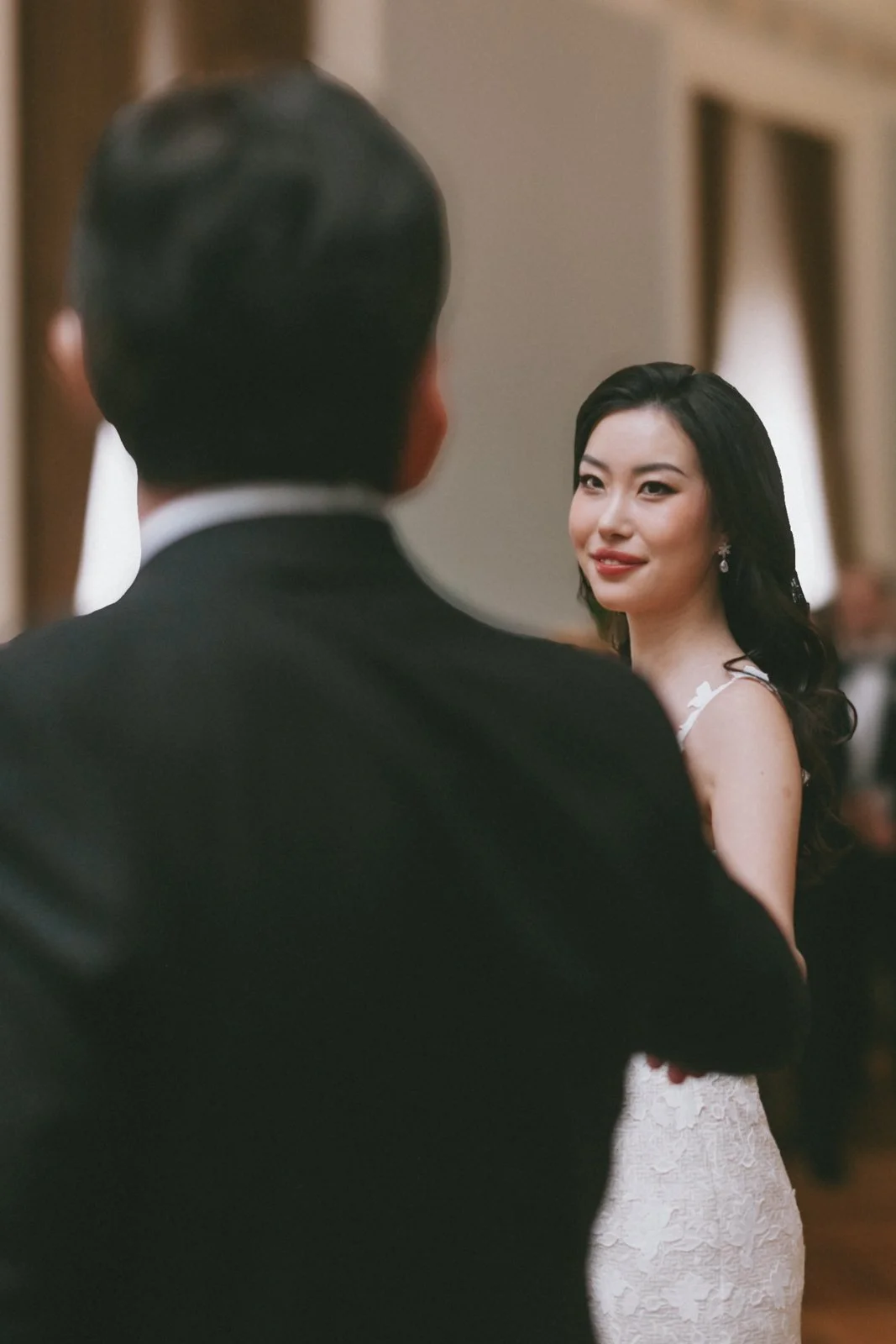 A woman in a wedding dress looking at a man in a tuxedo during a wedding ceremony.