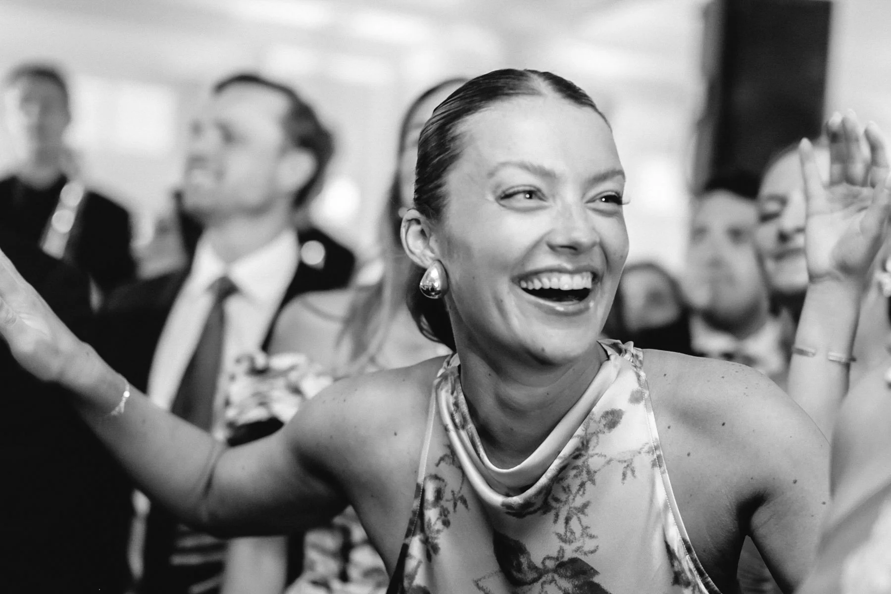 A woman laughing and enjoying herself at a social event, with others in the background.