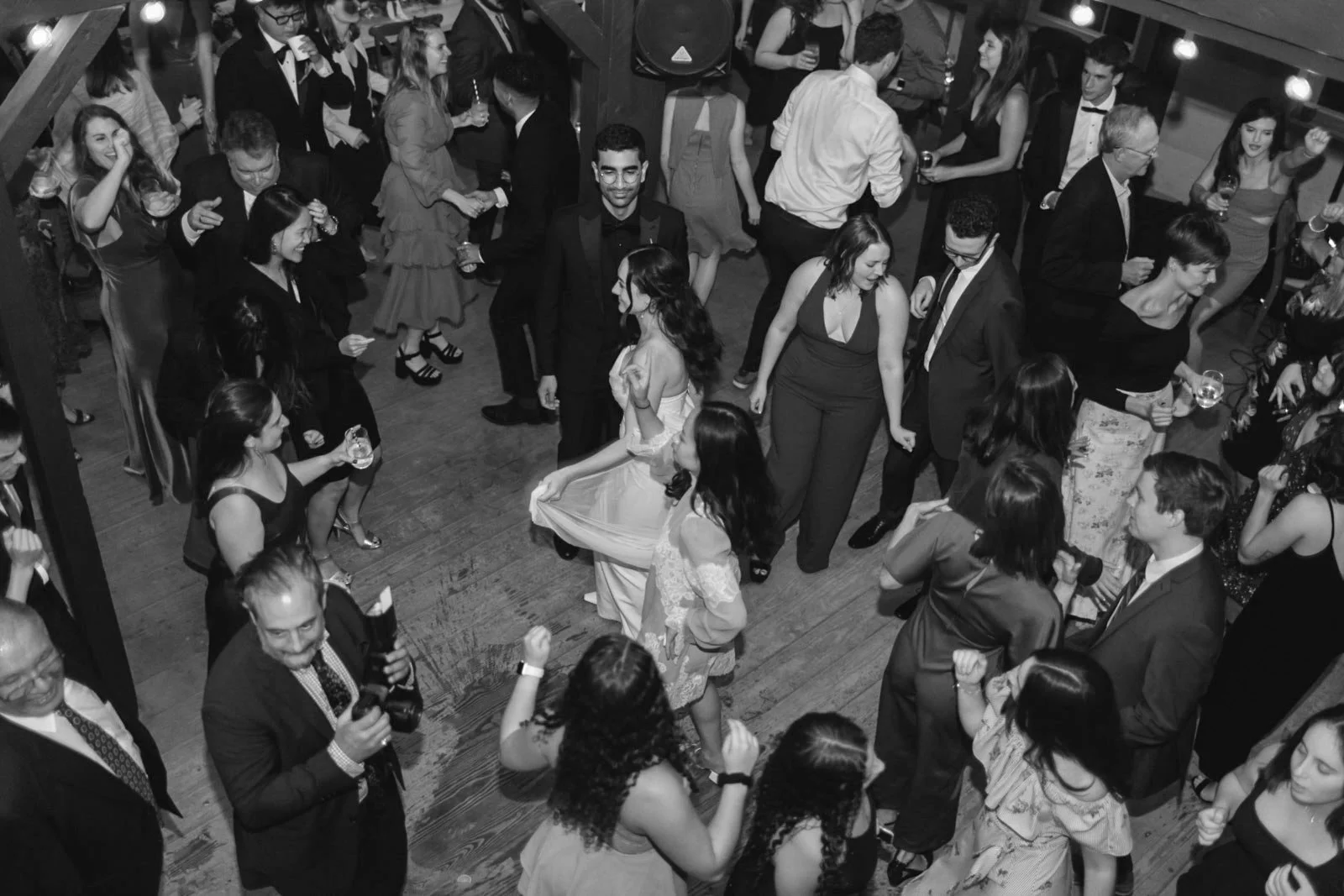 People dancing and socializing at a celebration or party in an indoor venue, dressed in formal attire.