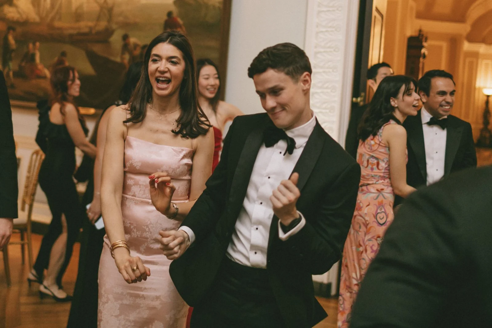 People in formal attire dancing and socializing at a party or celebration event.