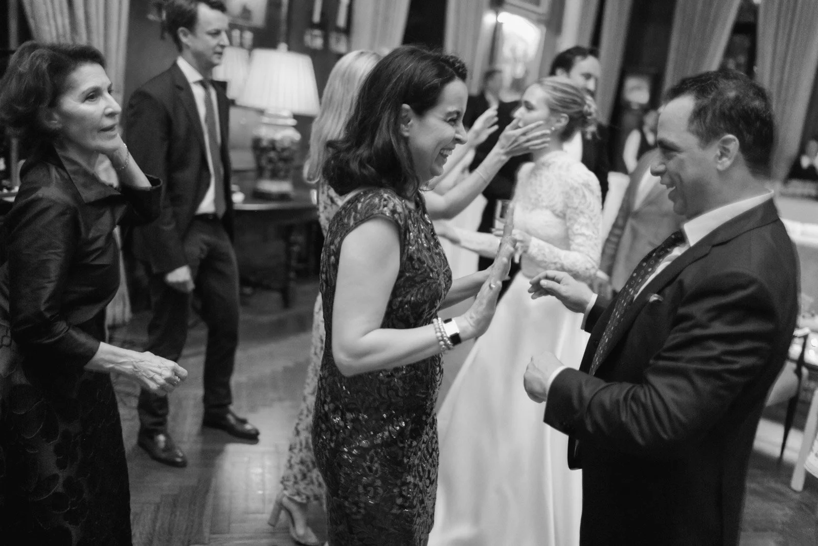 People dancing and socializing at an indoor event or party, with women and men wearing formal attire.