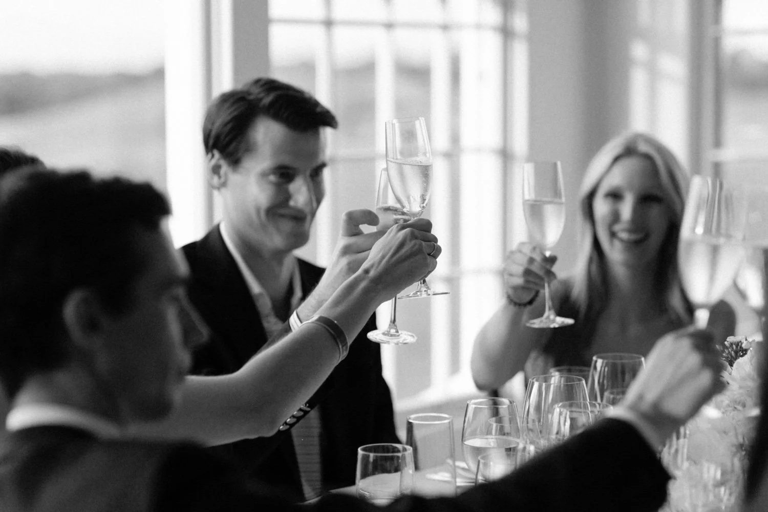 Group of people celebrating with champagne at a gathering, raising glasses in a toast.