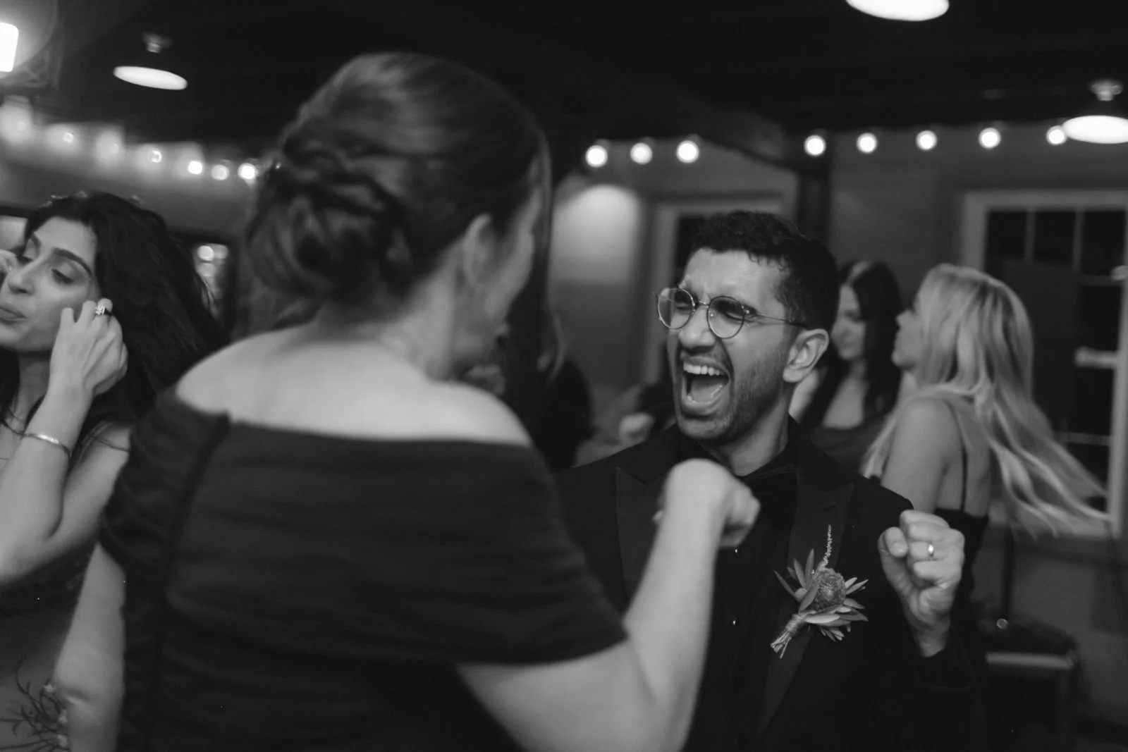 People celebrating and dancing at a party, with a woman and a man laughing and showing excitement.