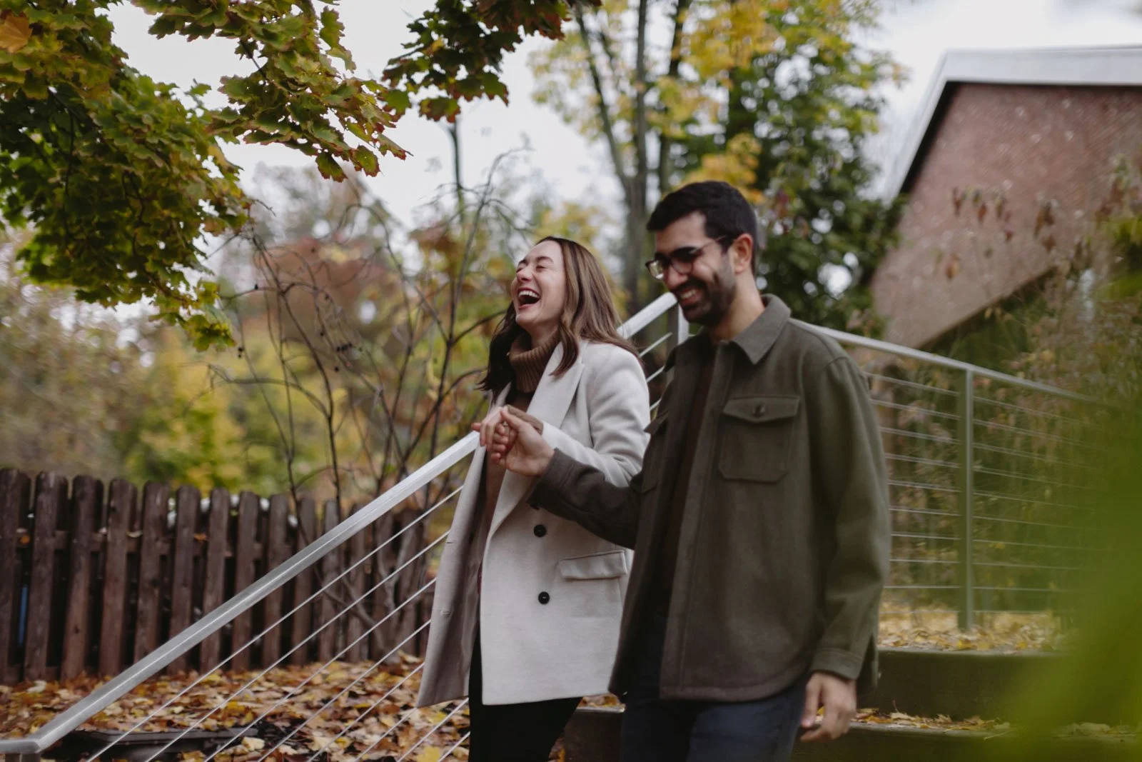 A smiling woman and man walking outdoors in autumn, holding hands, with trees at The Roundhouse at Beacon Falls.