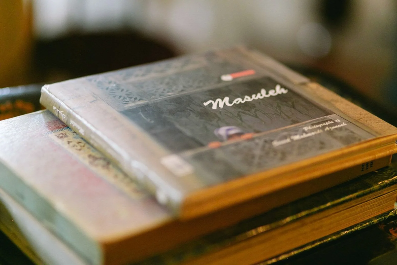 Close-up of a stack of books with one open, featuring a book titled 'MaruLeh' on top.