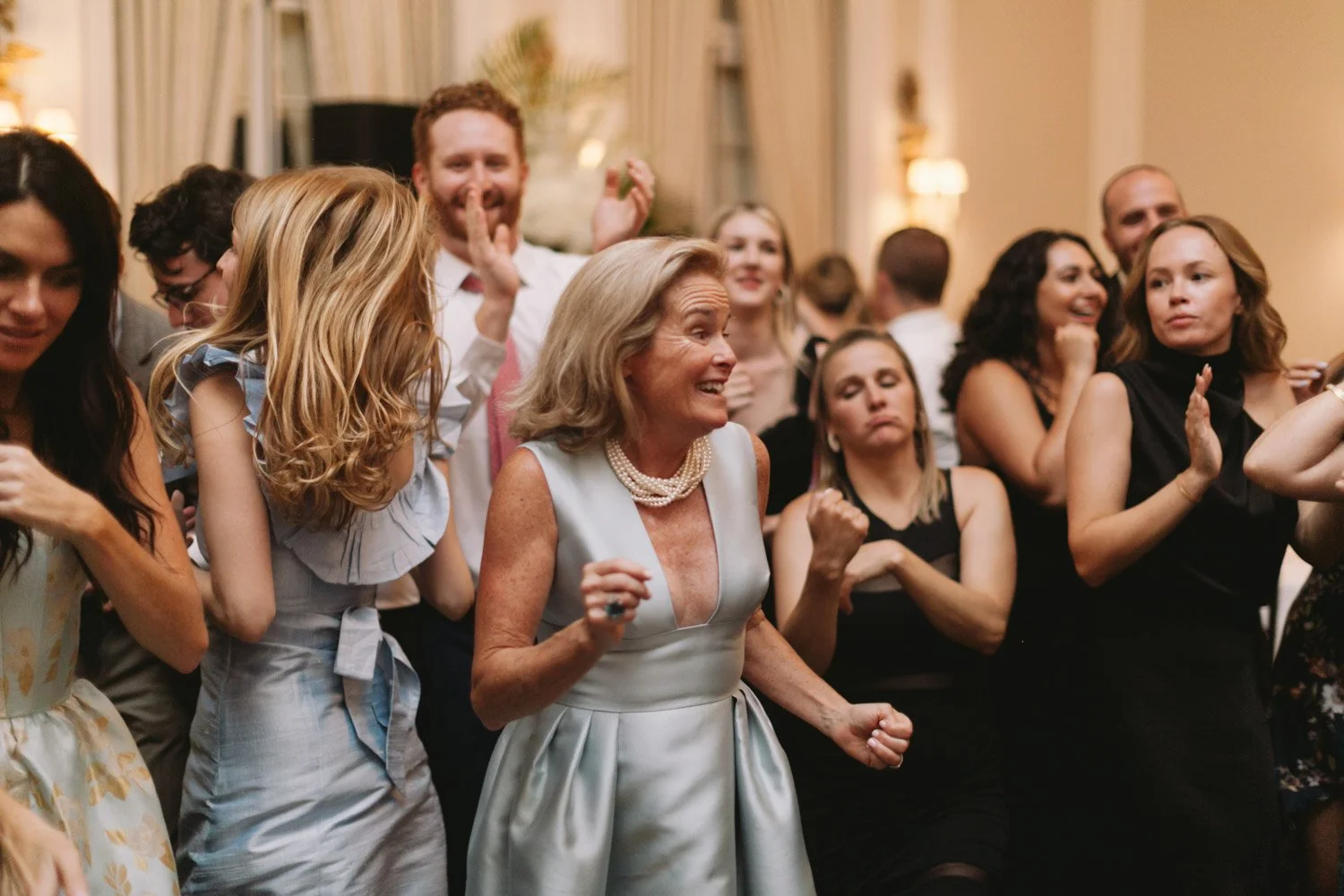 A group of people dancing and celebrating at a party or wedding reception.