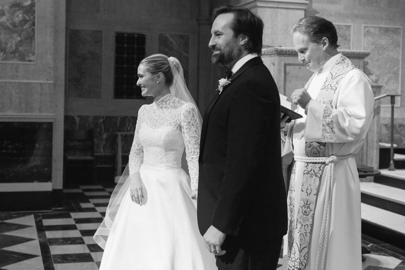 A bride and groom standing together during a wedding ceremony in a church, with a priest officiating.