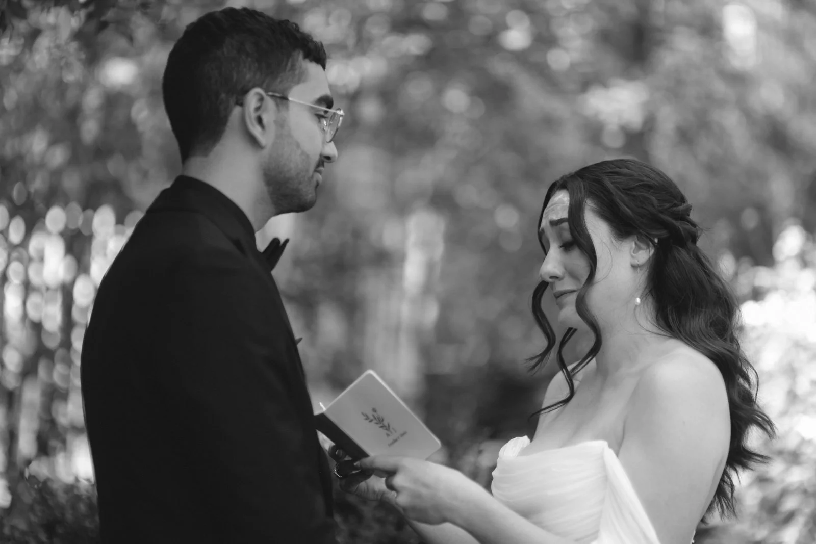 Black and white wedding photo of a bride reading vows to a groom outdoors at the Roxbury Barn and Estate.