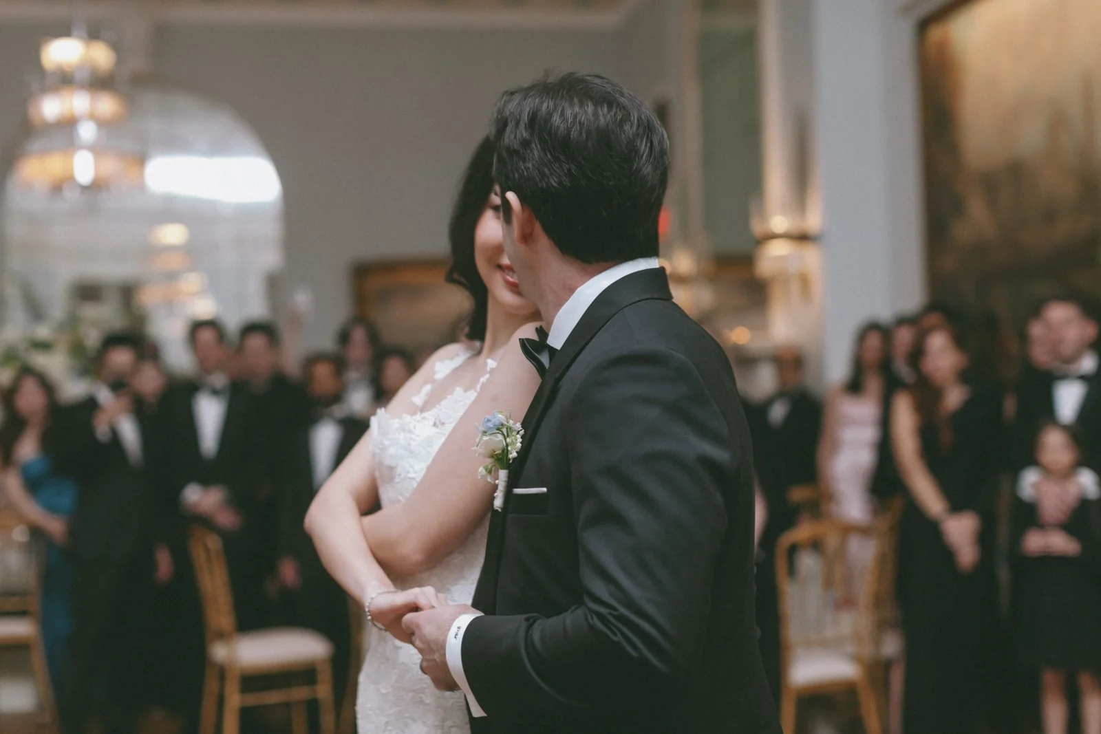 A bride and groom sharing a moment during their wedding ceremony, surrounded by guests in an elegant venue.