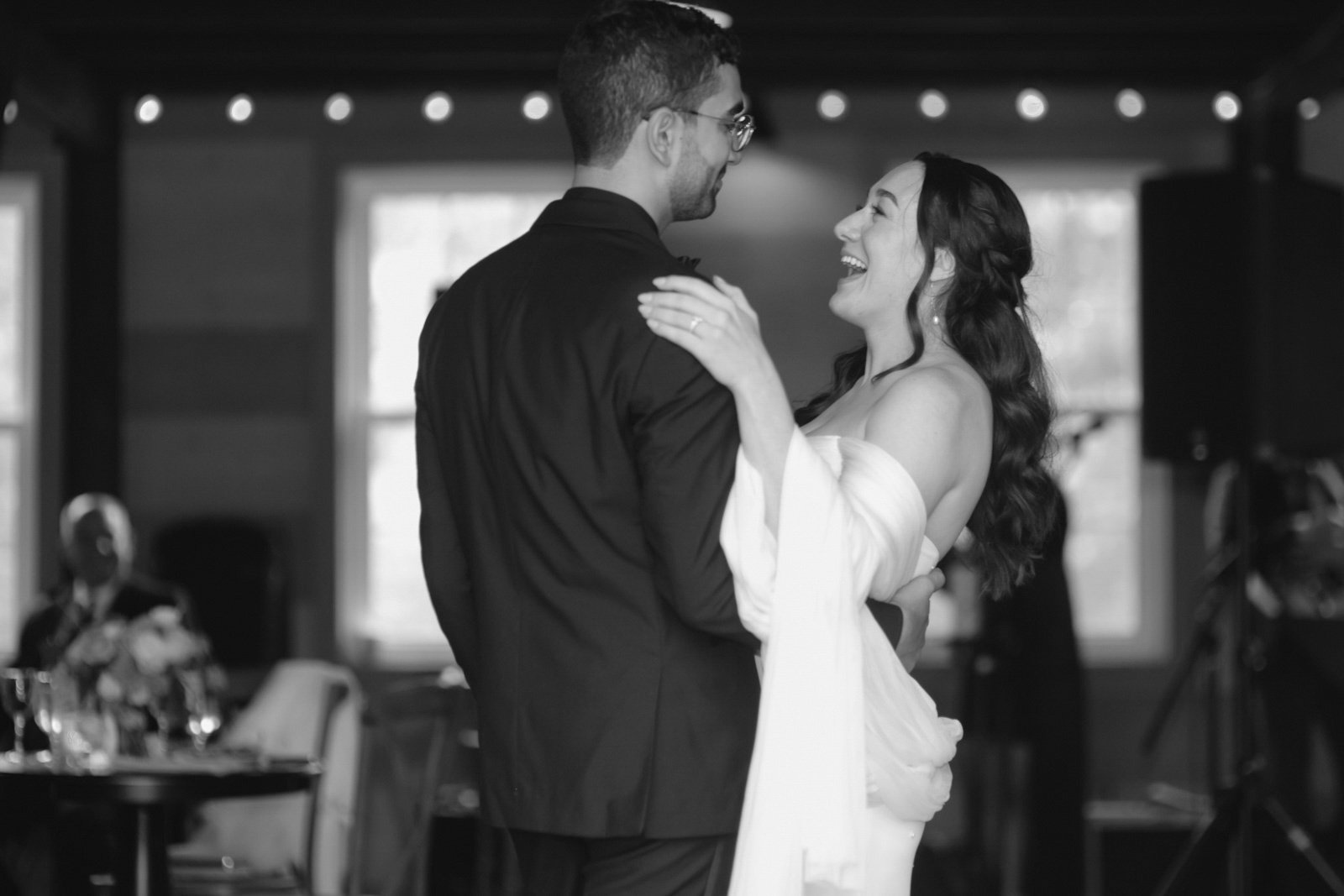 A couple dancing at their wedding reception, the bride and groom smiling at each other in a joyful moment.