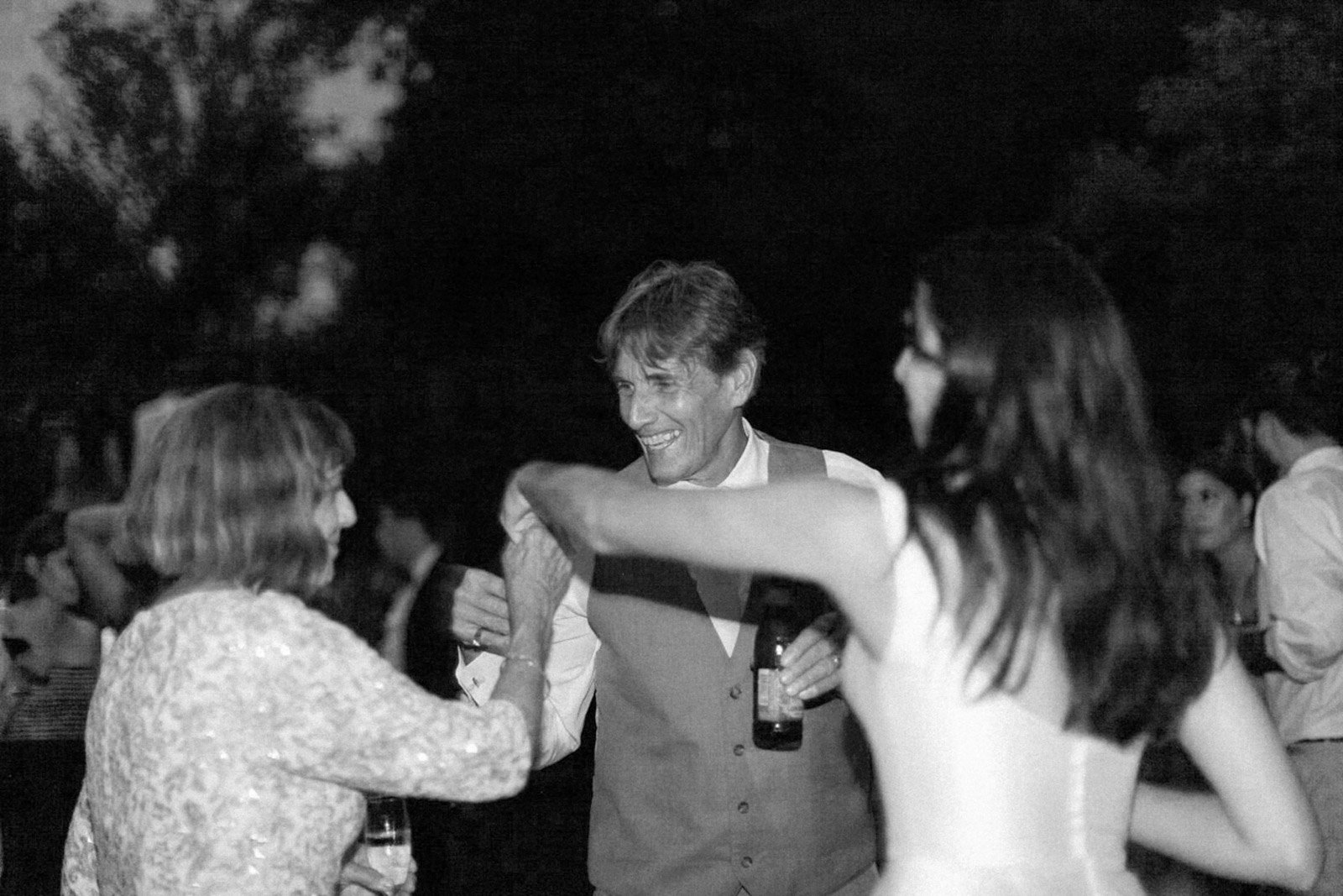 People dancing and socializing at an outdoor evening event, smiling and enjoying themselves.