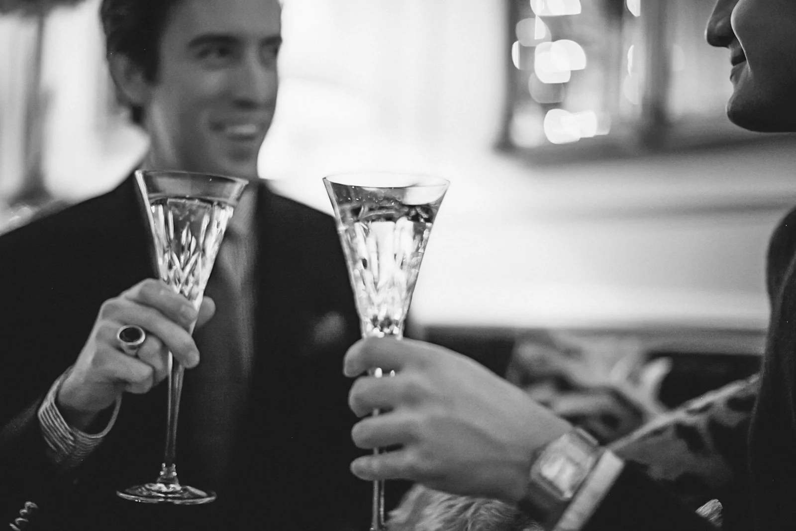 Two people, one man and one woman, holding up champagne glasses and toasting at a social gathering.