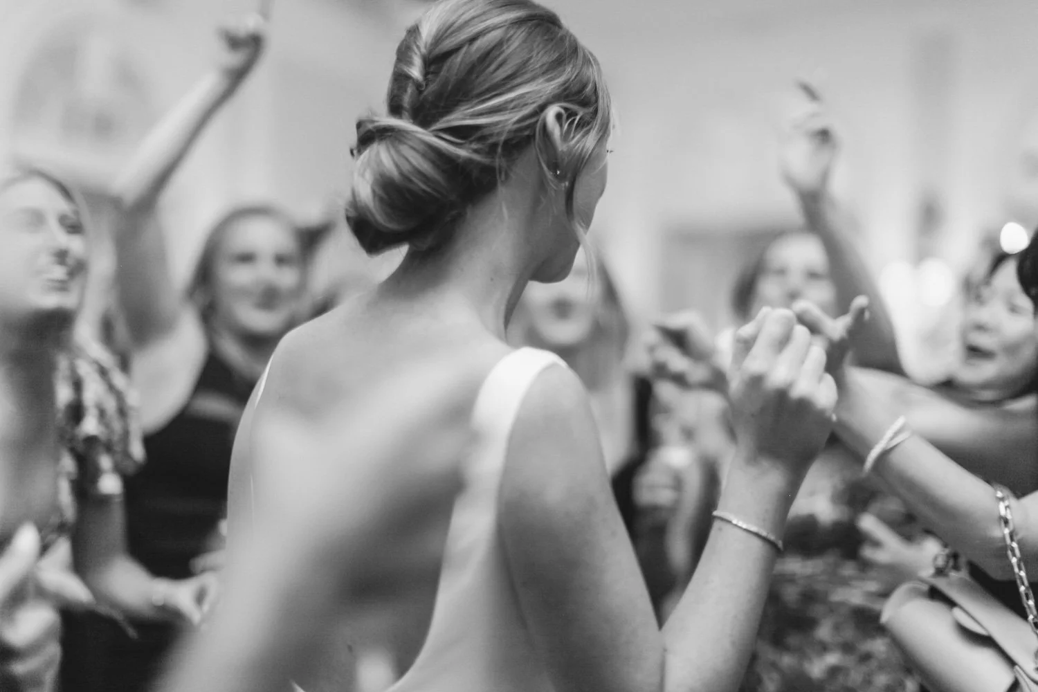 Group of women, with one woman in the foreground, and one woman in the background raising her arm, at a social event or party.