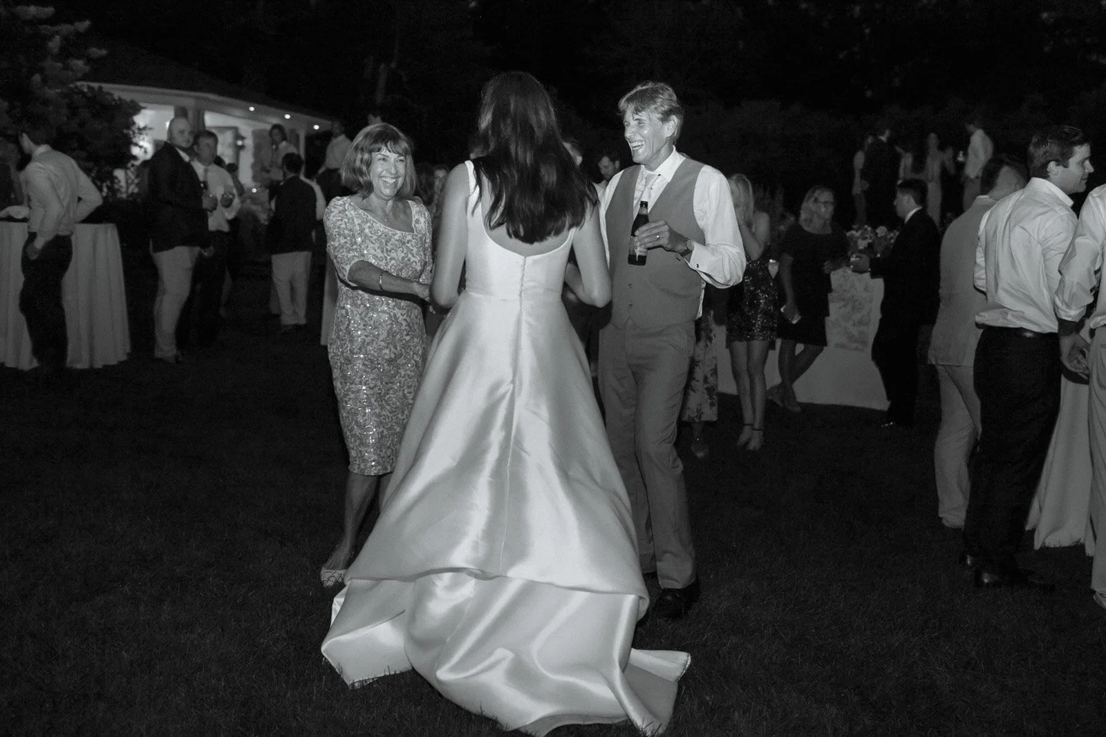 People dancing and socializing at a nighttime outdoor wedding reception.