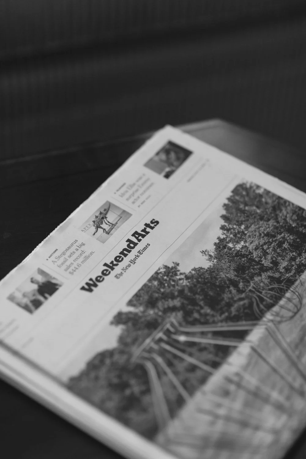 A black and white photo of a newspaper titled "Weekenders" with a large image of trees and a pathway on the front page.