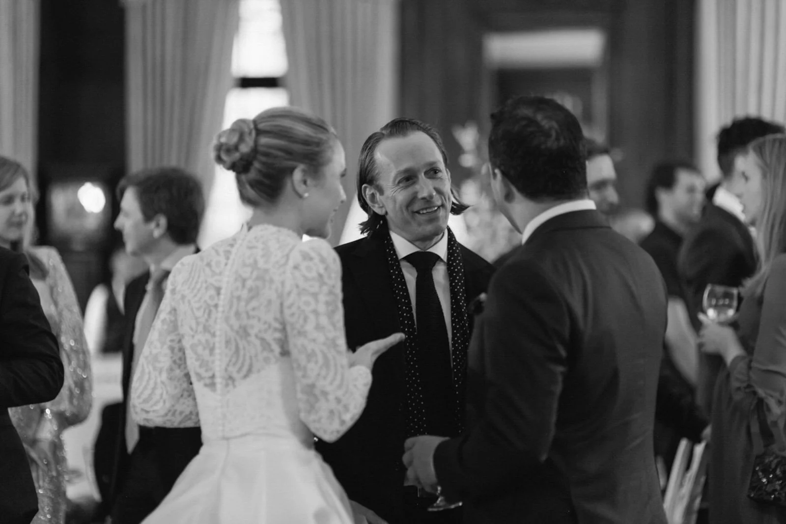 People at a social event, talking and holding drinks, in a formal setting.