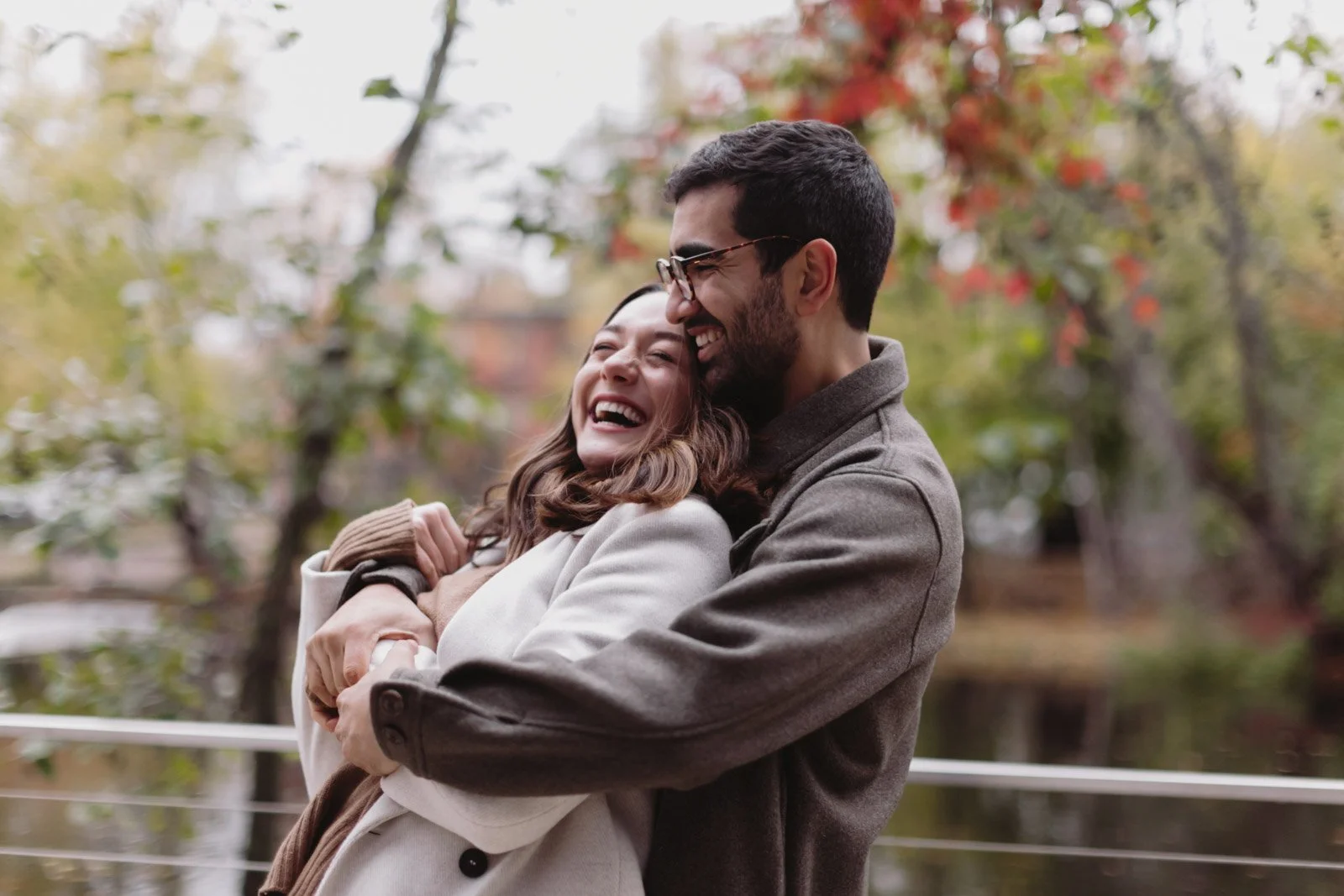 A young couple sharing a joyful embrace outdoors in autumn, surrounded by colorful fall foliage.