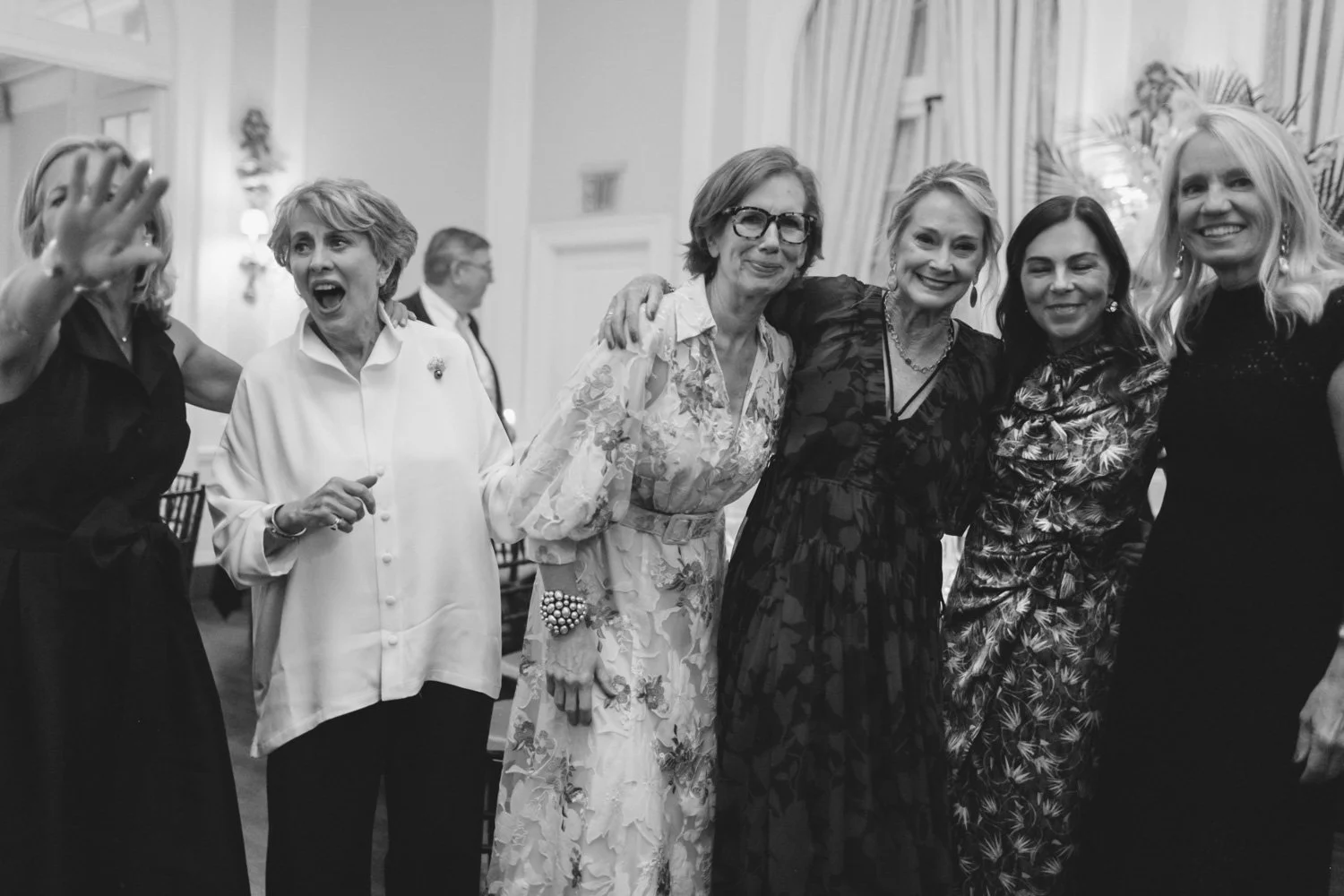 Group of women at a social event, smiling and posing for a photo in an elegant indoor setting.