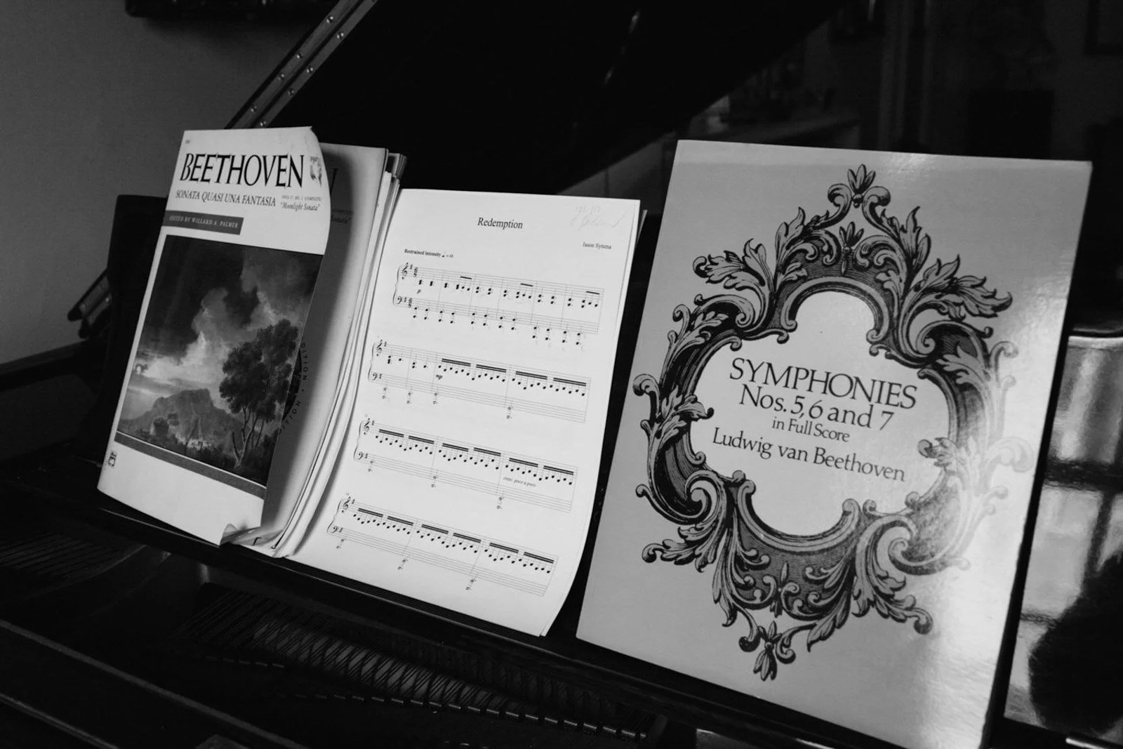 Sheet music and a book titled 'Symphonies Nos. 5, 6, and 7 in Full Score' by Ludwig van Beethoven on a music stand.