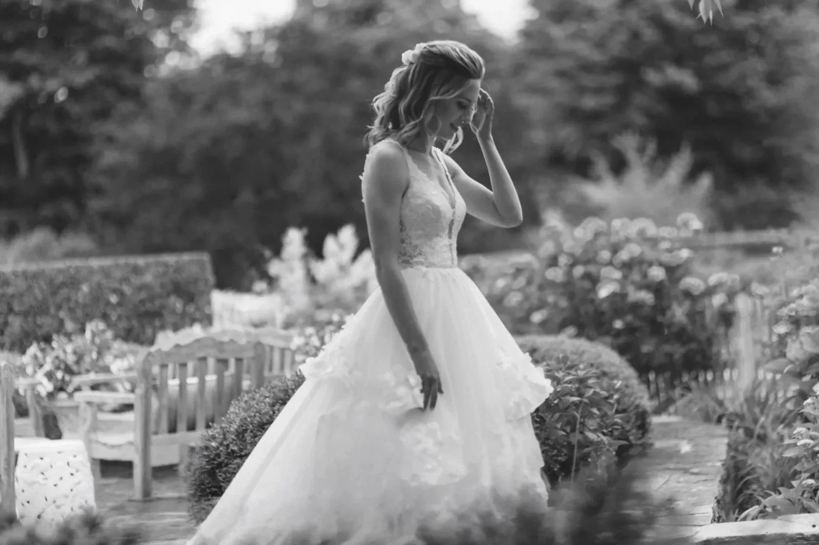 A woman in a wedding dress walking outdoors in a garden.