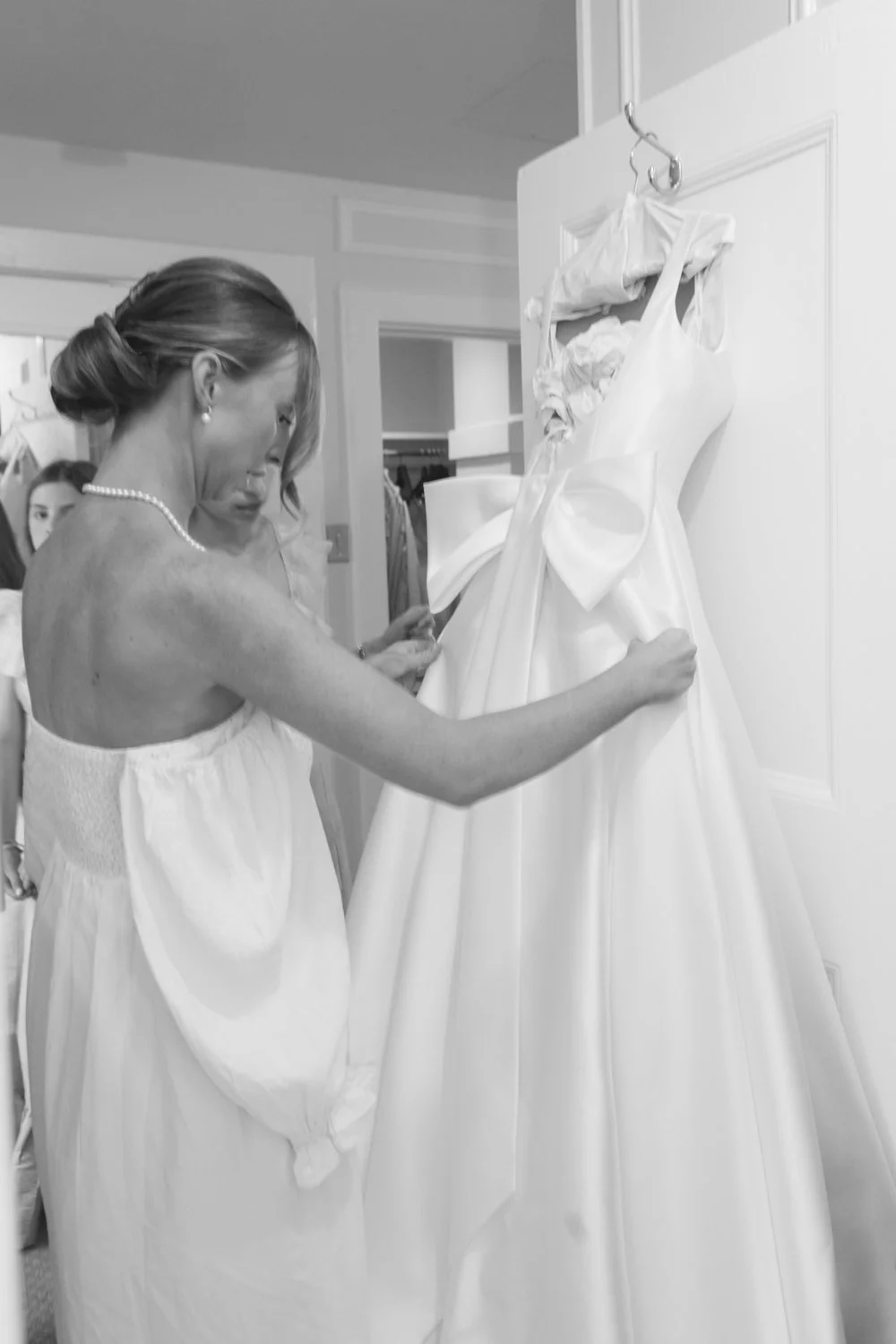 Bride in wedding dress inspecting gown with a seamstress.