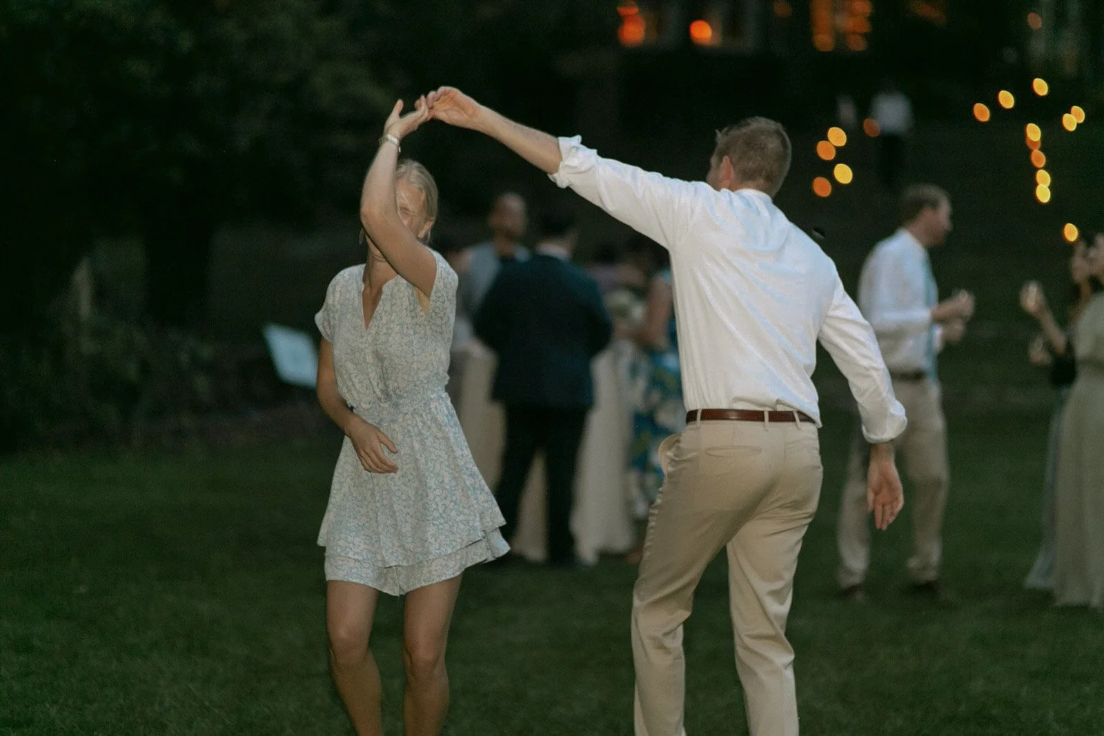 A man and woman dancing together outdoors at night, with other people in the background.