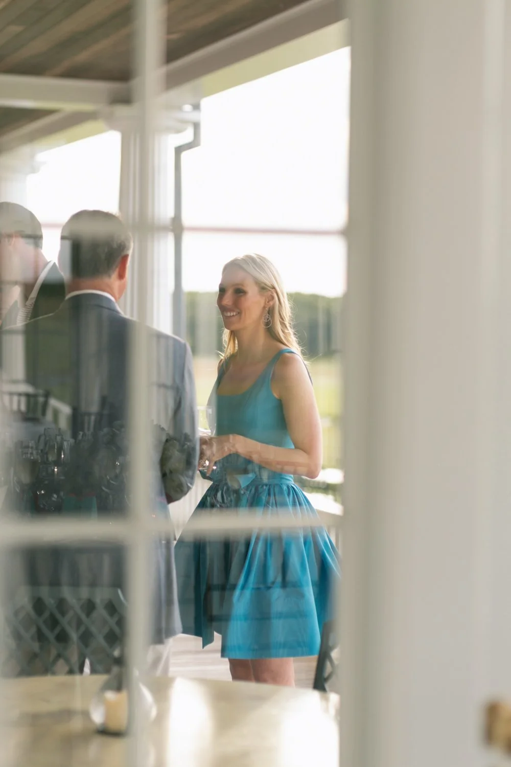 A woman in a blue dress smiling while talking to a man in a suit during an outdoor event.
