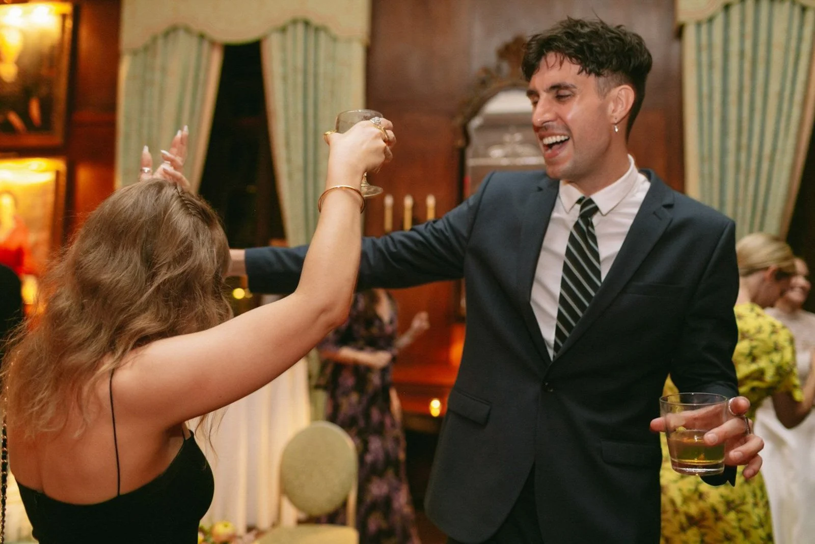 A man and woman enjoying a toast at a celebration in an elegant, warmly lit room.