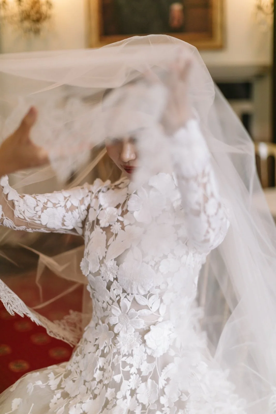 A woman in a white lace wedding dress is adjusting her veil.