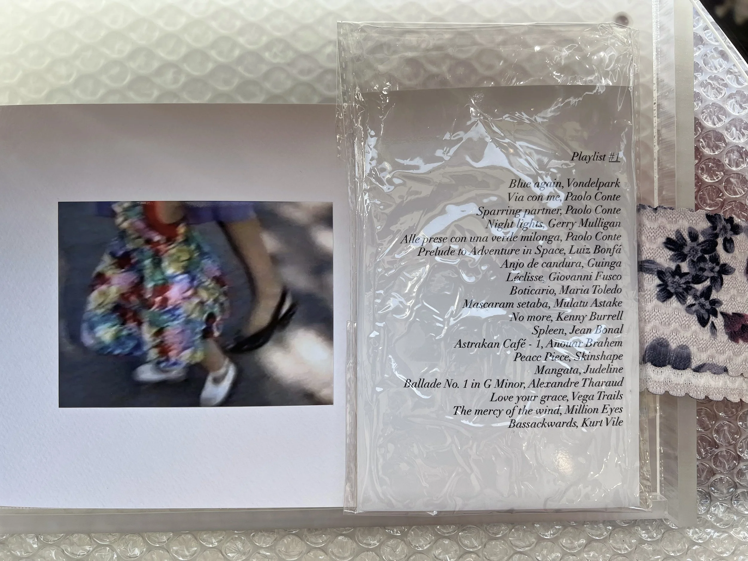    Home Movie Stills , 2025  Plexiglass box, glossy prints, textile fragment, playlist (three generations), pastel drawing. 