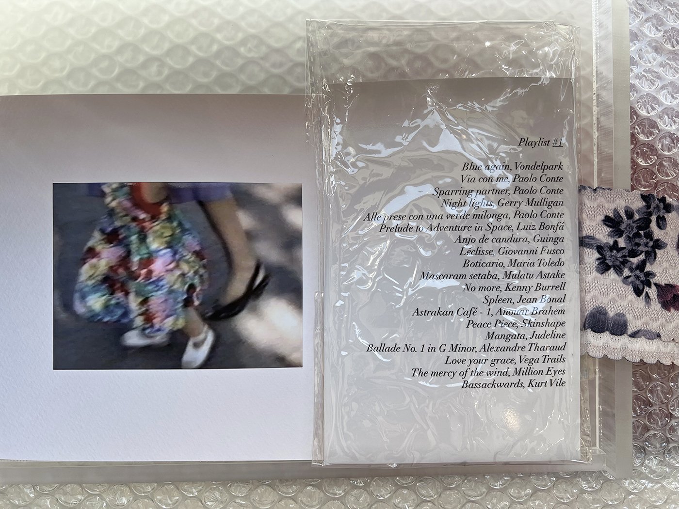    Home Movie Stills , 2025  Plexiglass box, glossy prints, textile fragment, playlist (three generations), pastel drawing 