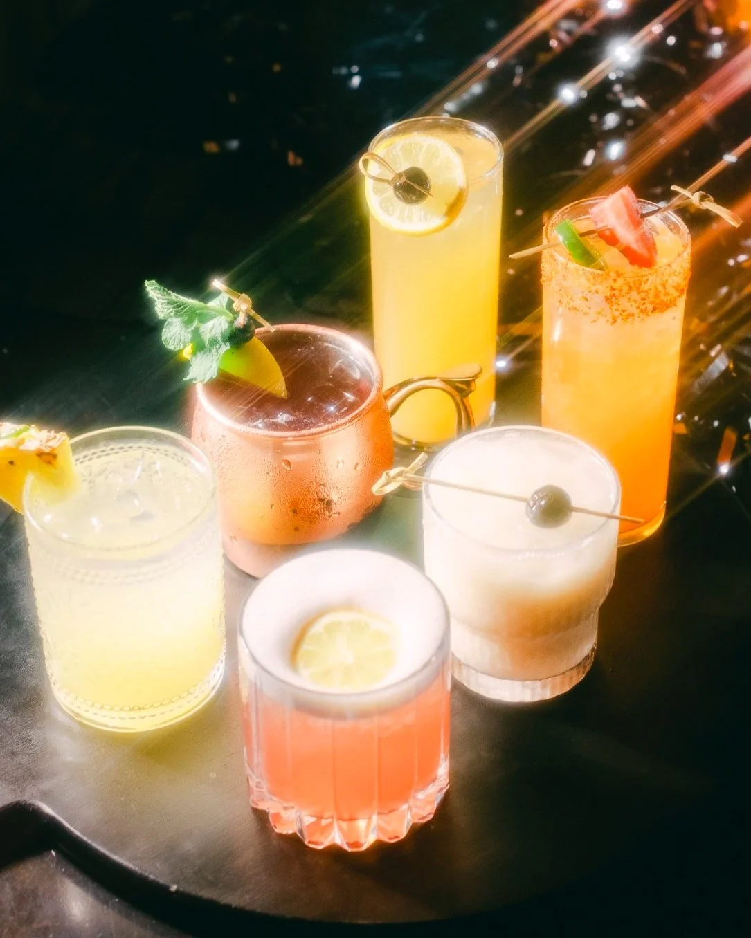 Six vibrant cocktails for Petit and Keet's Late Night Happy Hour launch. Colorful drinks with unique garnishes showcase the exclusive offerings available Thursday-Saturday, 9 PM-12 AM.