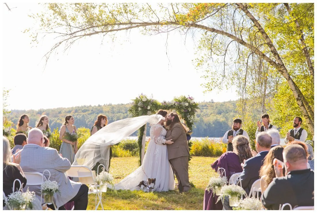 bride and groom kiss at end of ceremony, with veil floating up dramatically in the wind