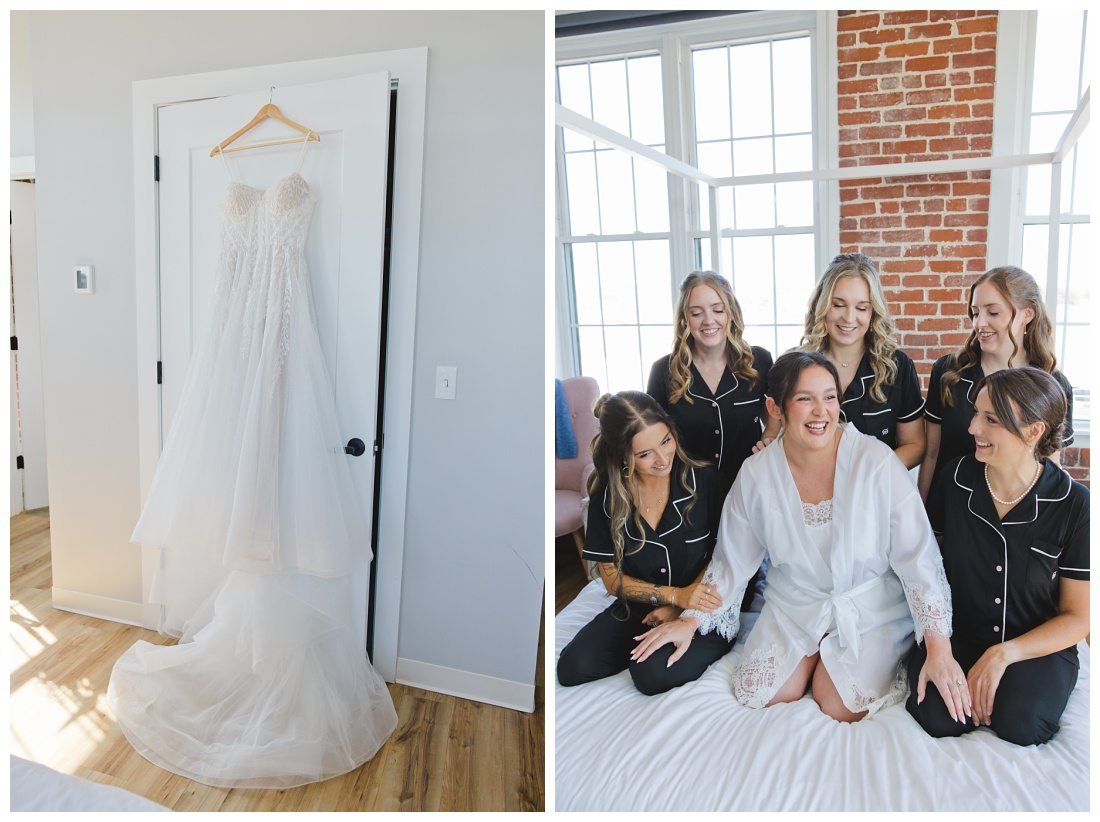 wedding dress hangs from back of closet, bride and her bridesmaids in white and black pajamas on the bed laughing
