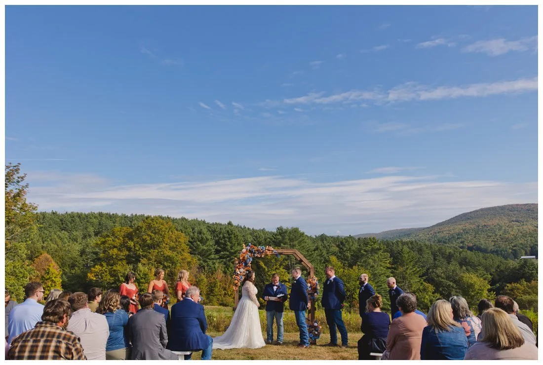 wide angle view of wedding ceremony at jeffers hill farm with mountains in the background and blue sky