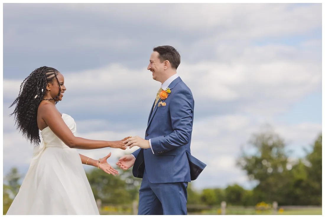 bride and groom hold hands and smile widely after first look