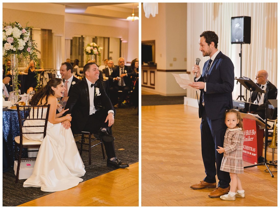 little girl holds on to her dad's leg as he gives wedding toast to laughing bride and groom