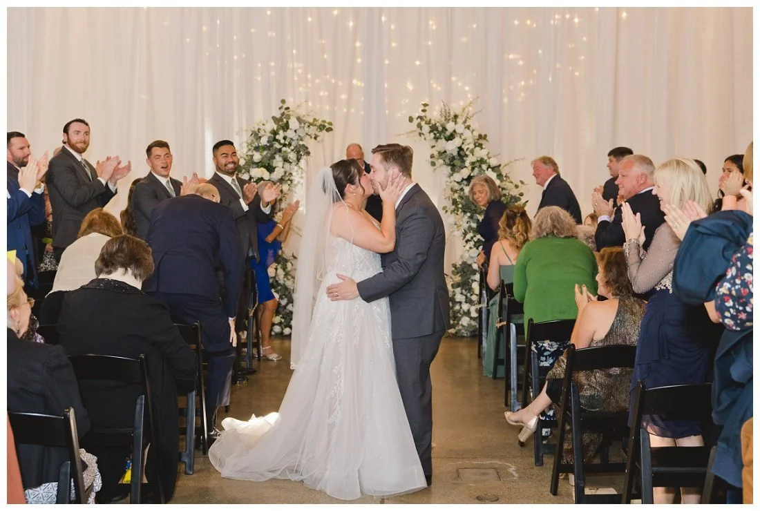 bride and groom kiss halfway down the aisle after ceremony