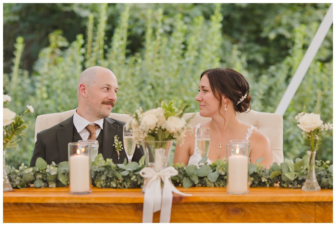 bride and groom look at each other with tenderness during wedding toasts
