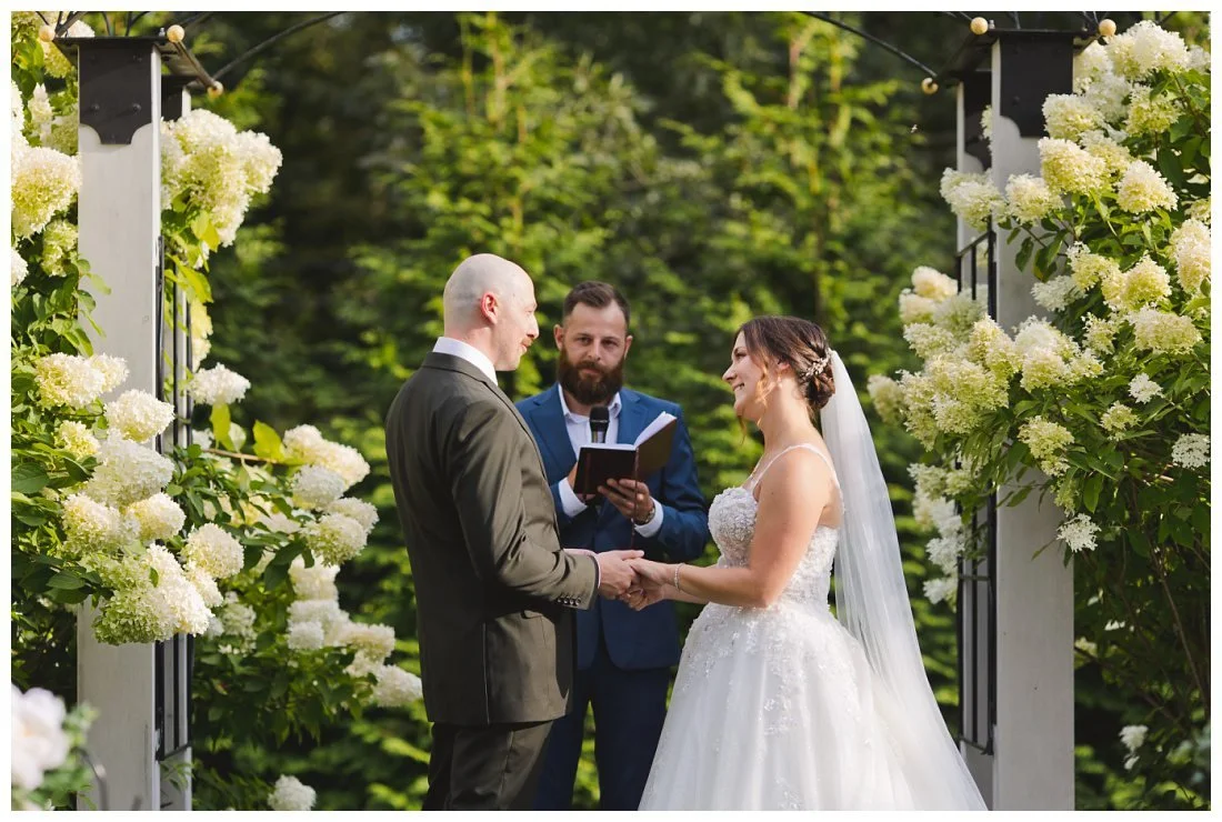 bride and groom exchange vows surrounded by beautiful white hydrangea bushes at their wedding
